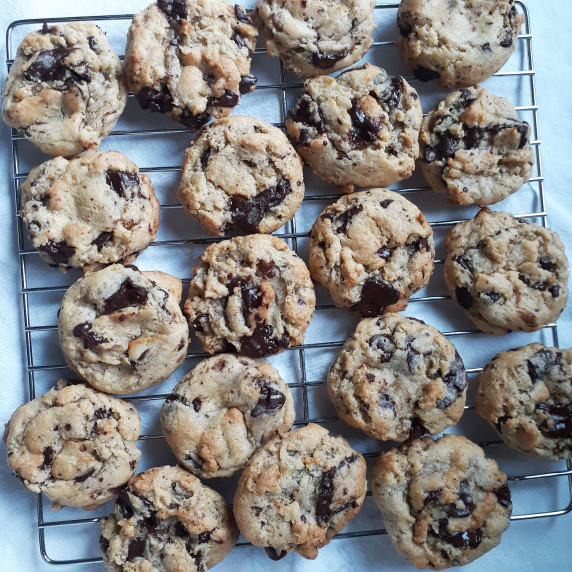 Gluten free chocolate chip cookies on a cooling rack with a white background