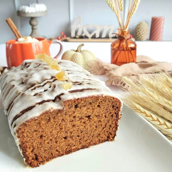 Close 45 degree shot of white platter housing a golden gingerbread loaf cake with end cut off.