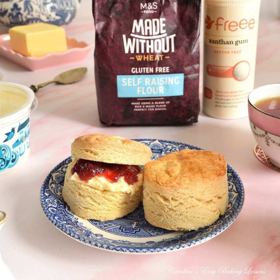 Table with blue vintage plate with 2 gluten-free air fryer British scones, 1 with jam & cream.
