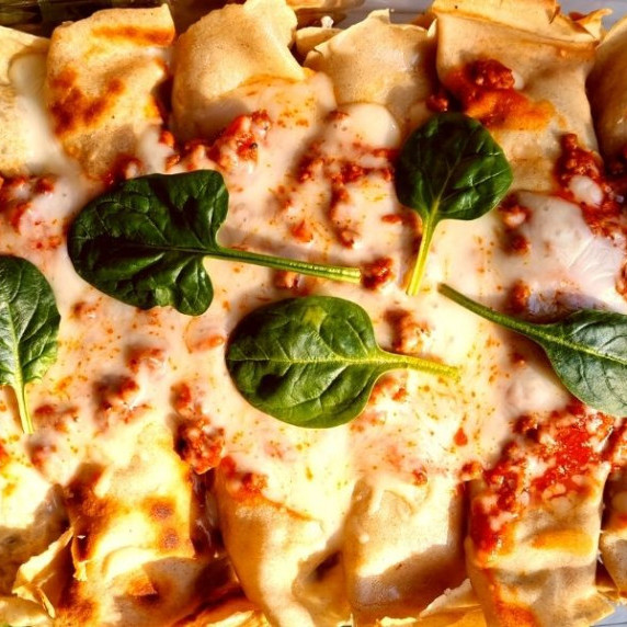 Crepes with cheese and bolognese on top with spinach.