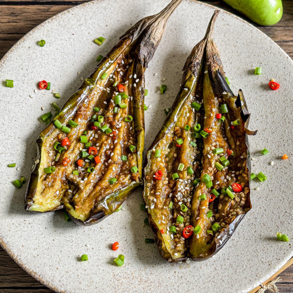 Grilled eggplant topped with chili, green onions, and sesame seeds.