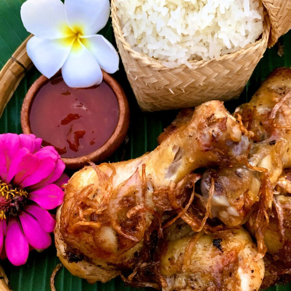 Top-down view of hat yai fried chicken with sticky rice and a dipping sauce.