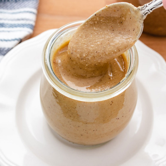 Hazelnut butter in a glass jar with a spoon.