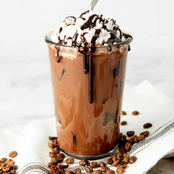 Iced Mocha in a glass topped with whipped cream and diy mocha syrup.