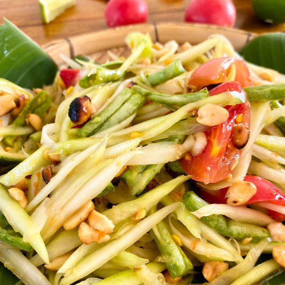 Som tam Thai with beans, tomatoes, peanuts, and green papaya slices.