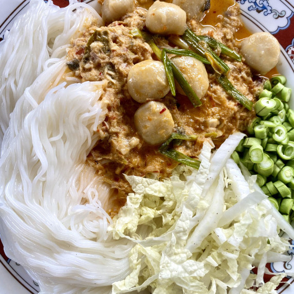 Fresh rice noodles with Thai fish curry and a side of fresh vegetables.