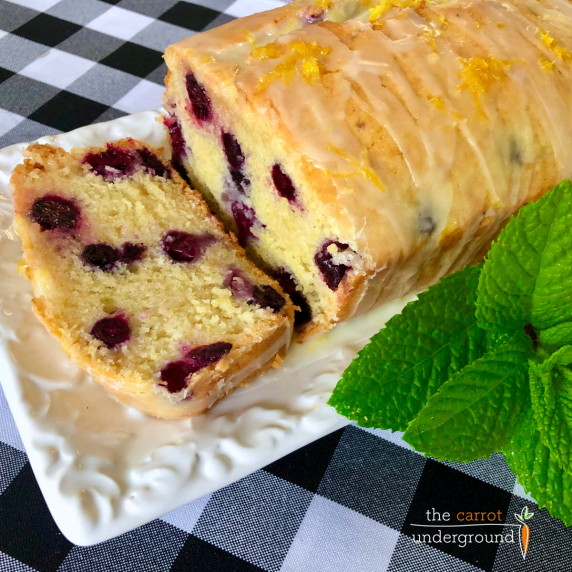 A loaf of vegan lemon blueberry bread topped with a lemon glaze and zest.