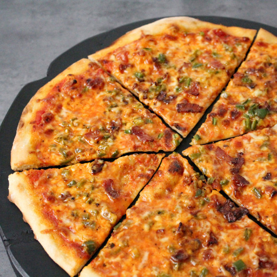 A cheese pizza topped with bacon, jalapeno, and maple syrup