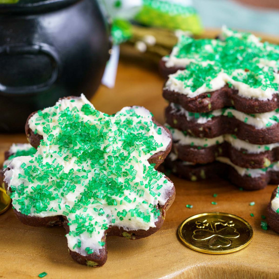 Shamrock shaped cookies with icing on a wooden board.