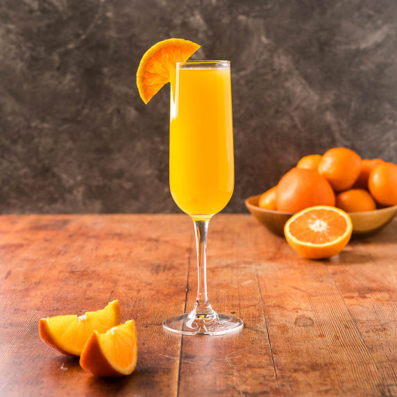 A champagne flute filled with a non-alcoholic mimosa garnished with an orange wedge