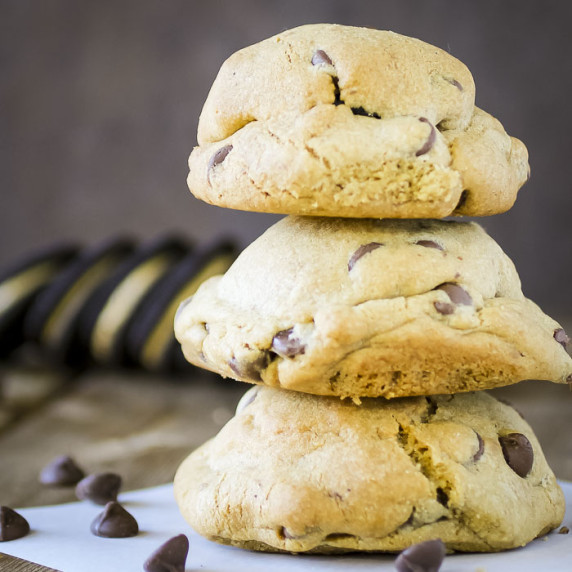 Side shot of three Oreo stuffed cookies stacked on each other with chocolate chips on the side. 