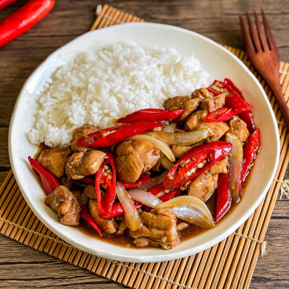 Top-view of pad prik gai, a Thai red curry chicken stir-fry, served with jasmine rice.