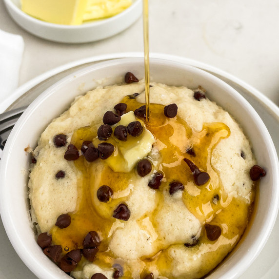 White cup with chocolate chip pancake, butter and syrup. 