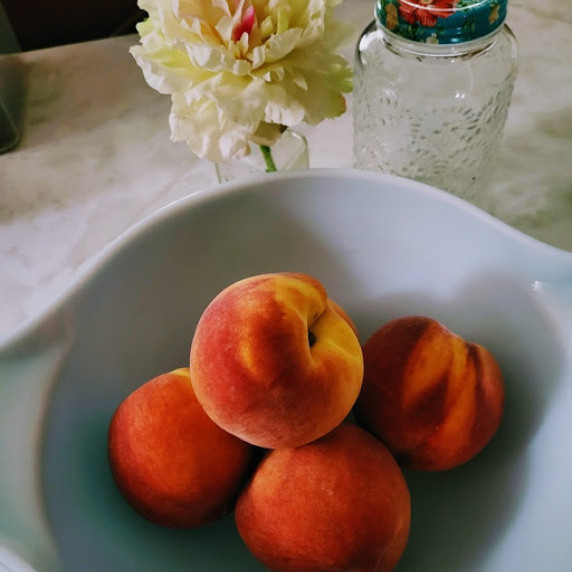 peaches setting in a blue Pyrex bowl on top of countertop 