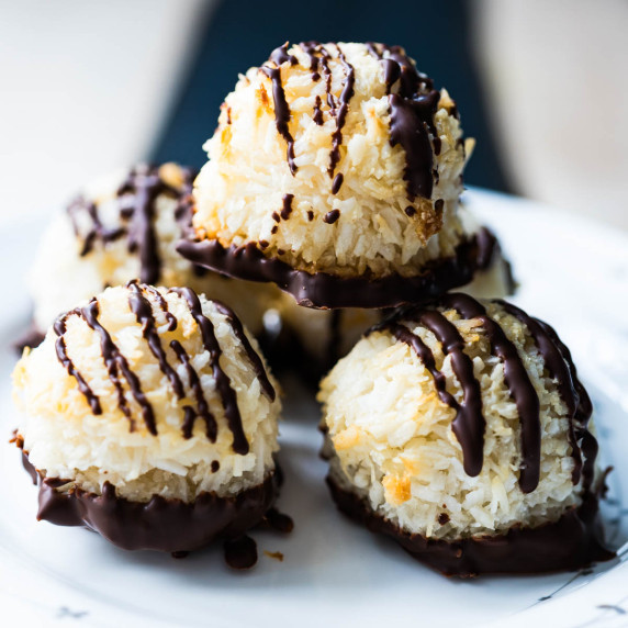 Five chocolate dipped macaroons on a plate with three stacked in a pyramid.