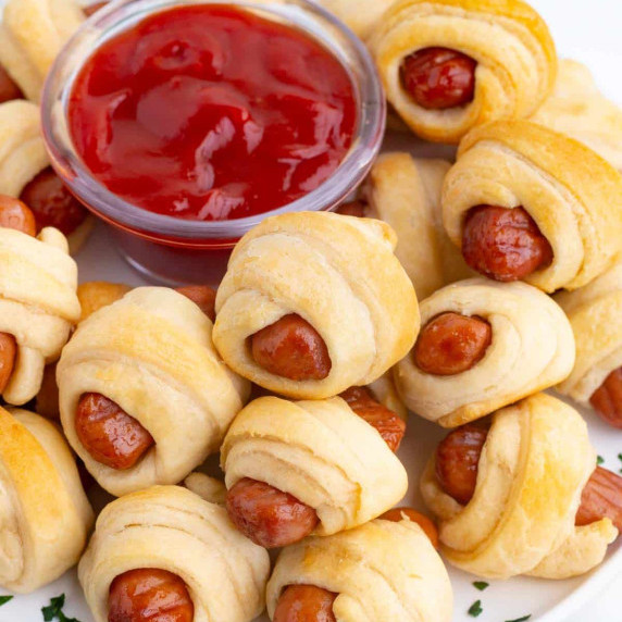 Pigs in a Blanket with Crescent Rolls RECIPE served with ketchup on a white plate.