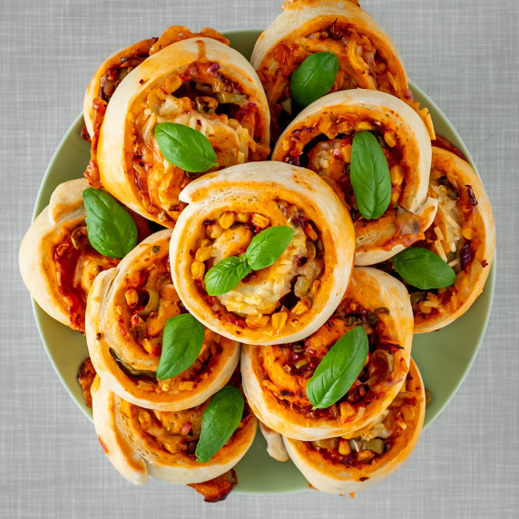 A plate full of pizza rolls, garnished with fresh basil