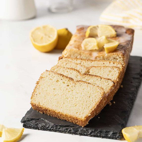 gluten free lemon pound cake on a dark surface with slices of lemon on top