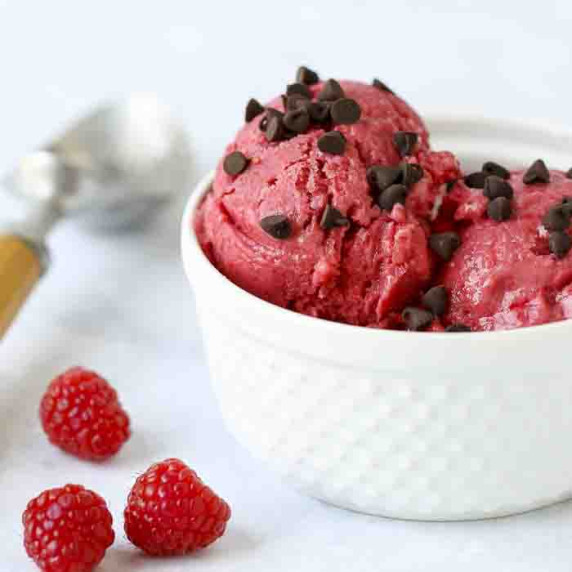 Side shot of raspberry frozen yogut with chocolate chips in a white bowl.
