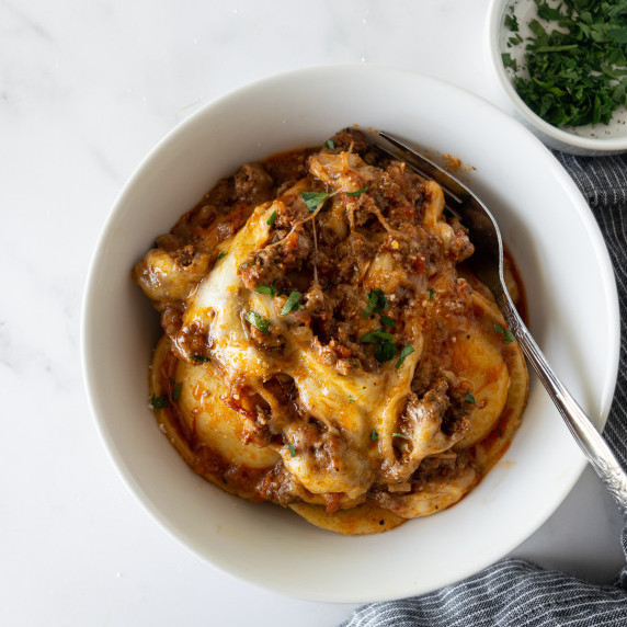 baked ravioli with melted cheese in a white bowl.