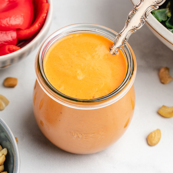 Roasted red pepper dressing in a glass jar with a spoon.