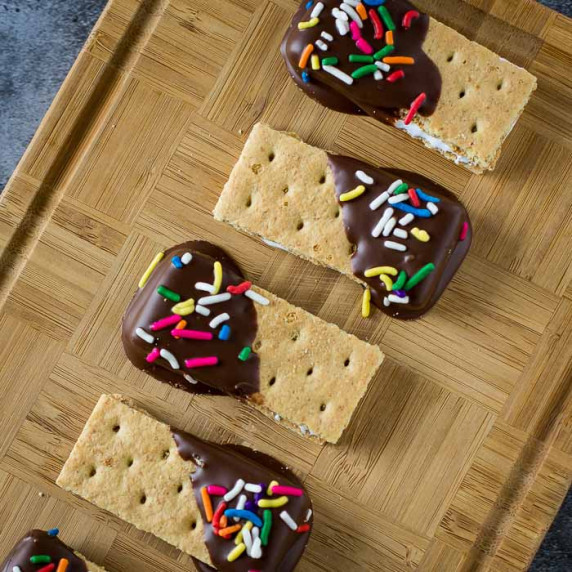 Overhead shot of s'mores bites in a row on a wooden cutting board.