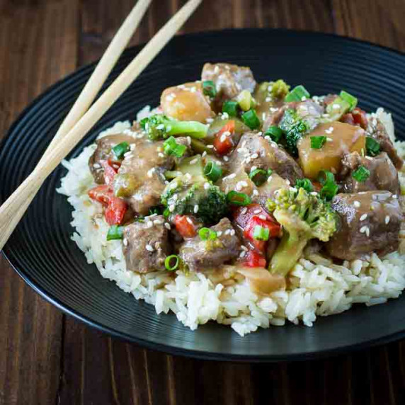 Side angled shot of beef teriyaki on a bed of white rice garnished with sesame seeds.