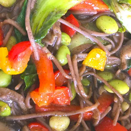 close up of soba noodle bowl showing soba noodles and veggies covered in ginger sauce