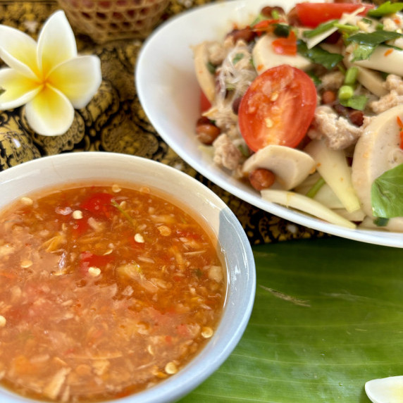 Thai salad dressing with salad in the distance.