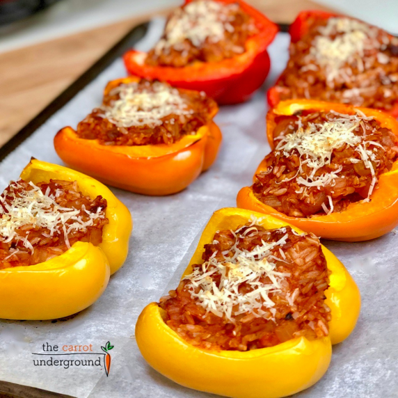 A baking pan with roasted red, yellow and orange bell peppers filled with vegan protein and rice.