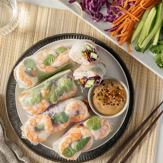 shrimp summer rolls on a white plate with peanut sauce on the side
