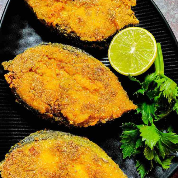 ready to eat seer fry served in a black dish garnished with celery and lemon by homemakerjob.com