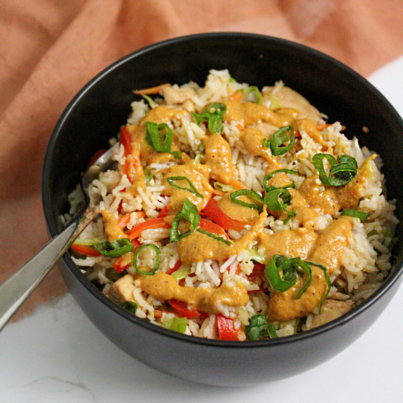 A Thai chicken and rice bowl with veggies and creamy peanut sauce