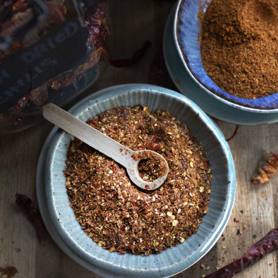 Chili flakes in a small bowl with a spoon in the middle.