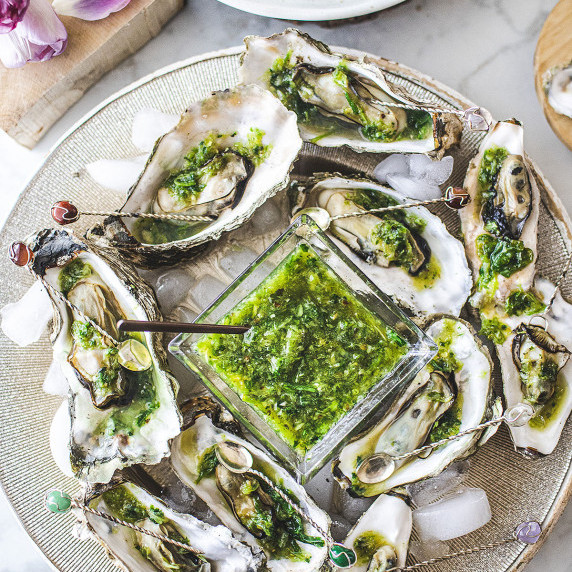 Oysters around a bowl of Thai green seafood sauce on a platter. 