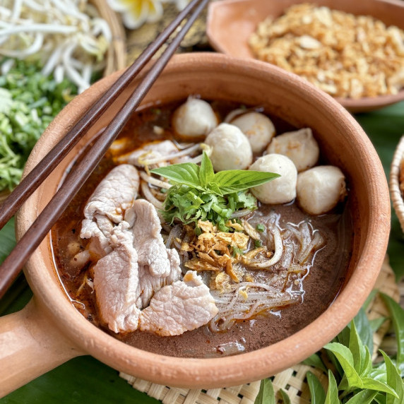 Thai boat noodles soup in a clay dish.