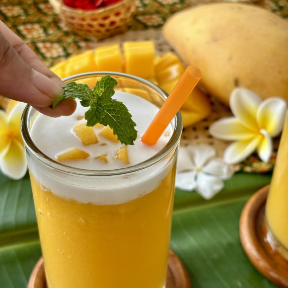 Garnishing mango shake with a mint leaf.