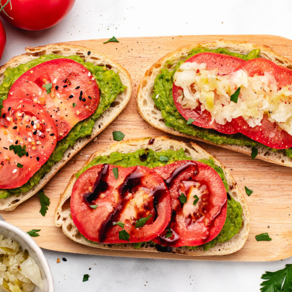 Three slices of toast with mashed avocado and sliced tomatoes.
