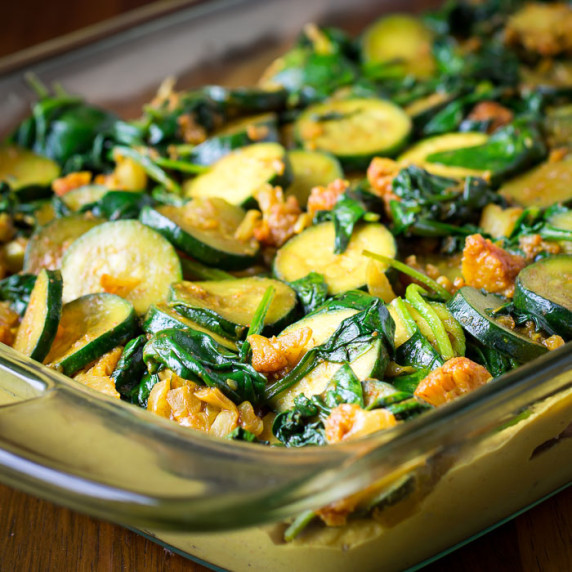 Overhead close up view of casserole in a clear cooking dish on a wooden surface.