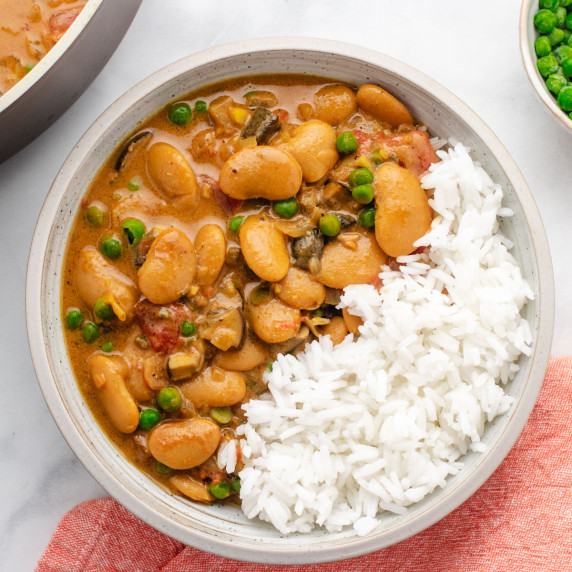 Butter bean curry with peas in a bowl with white rice.