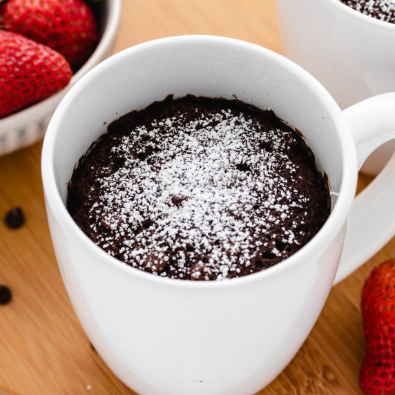 Chocolate mug cake in a white coffee mug with powdered sugar.
