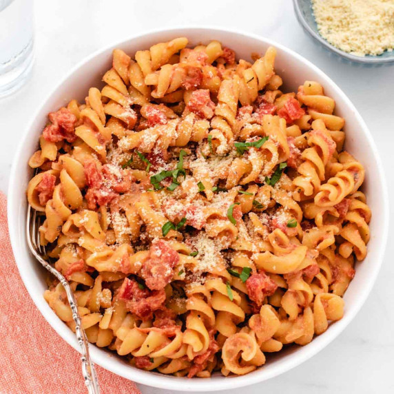 Creamy tomato pasta with basil and vegan parmesan in a bowl.