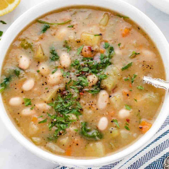 White bean potato soup in a bowl with chopped parsley.